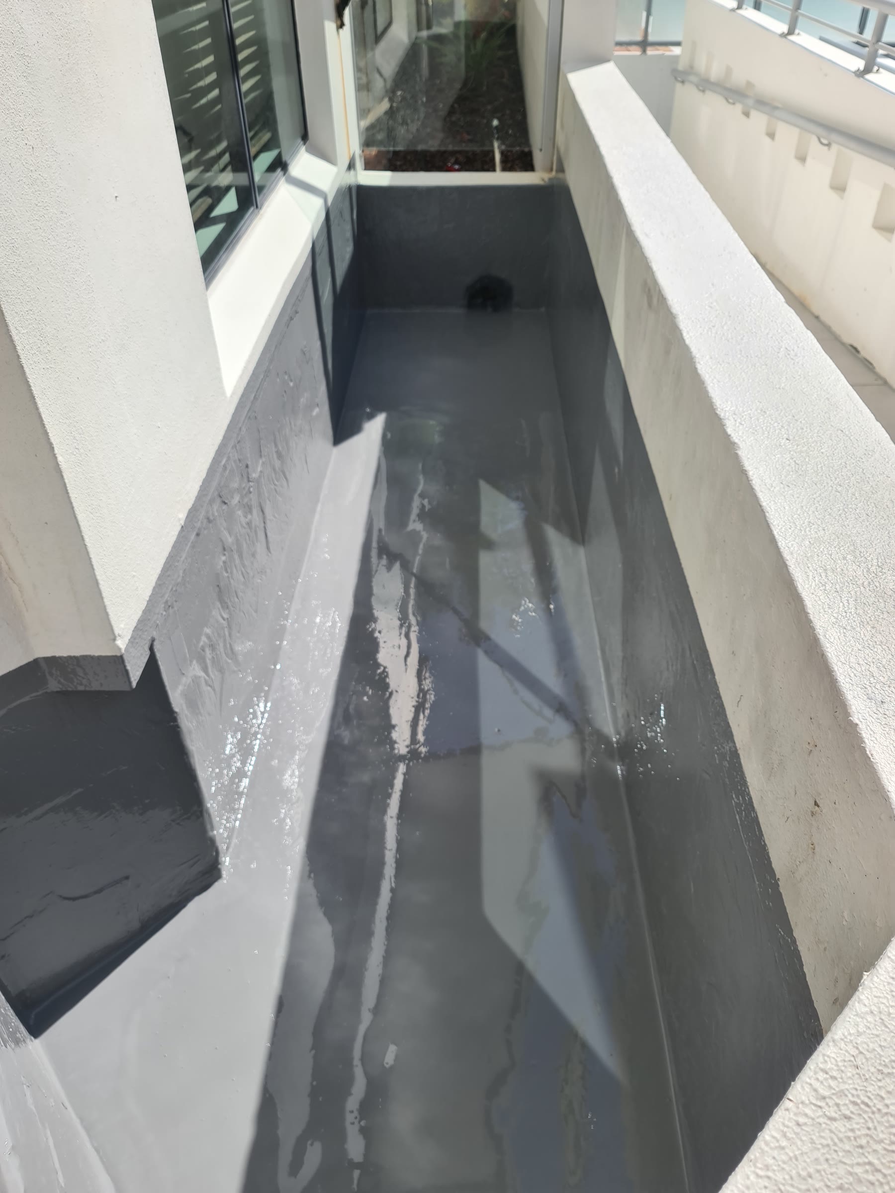 Long built-in planter box lined with dark grey waterproofing membrane