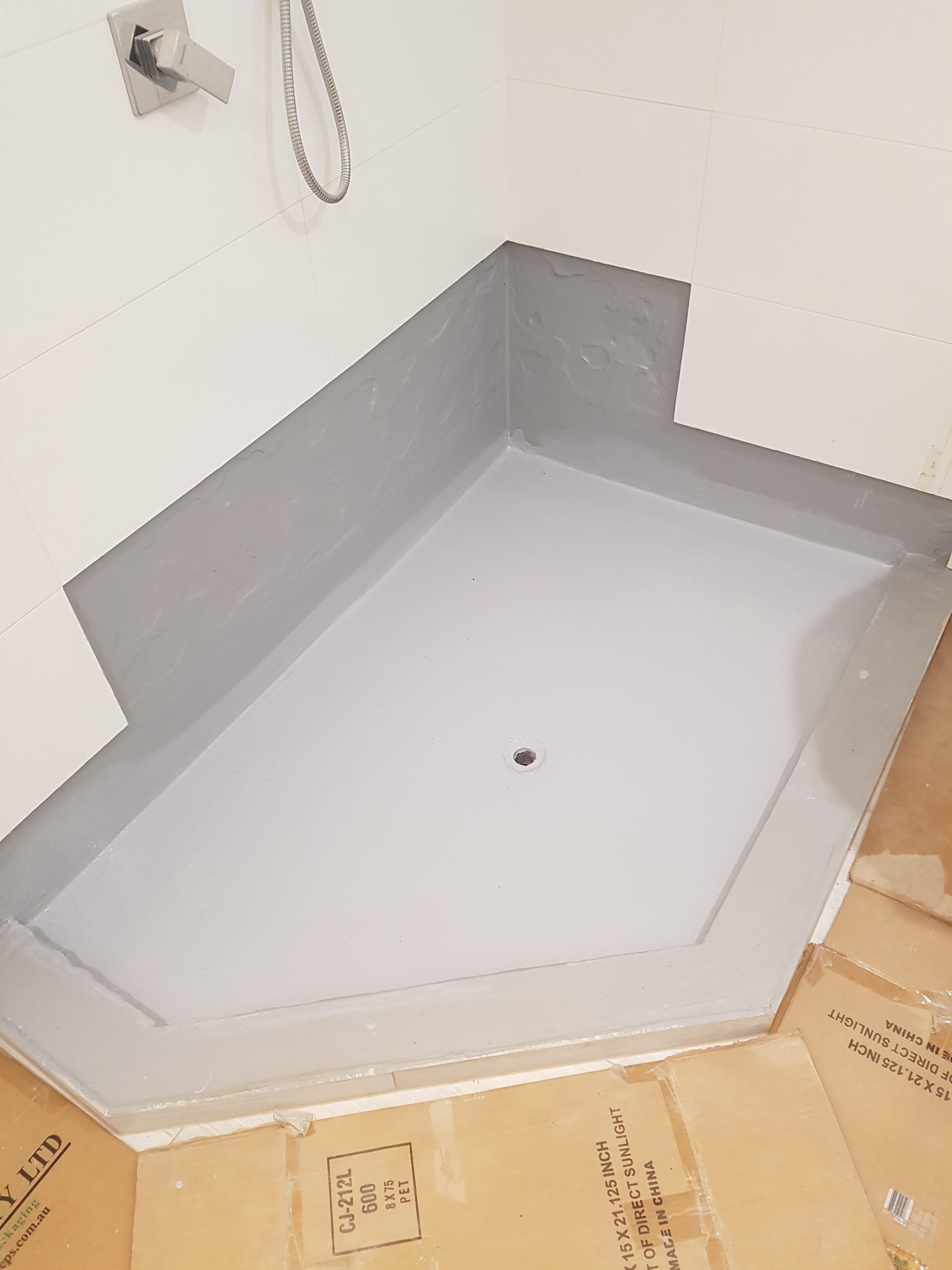 Shower base waterproofed with grey membrane before tiling